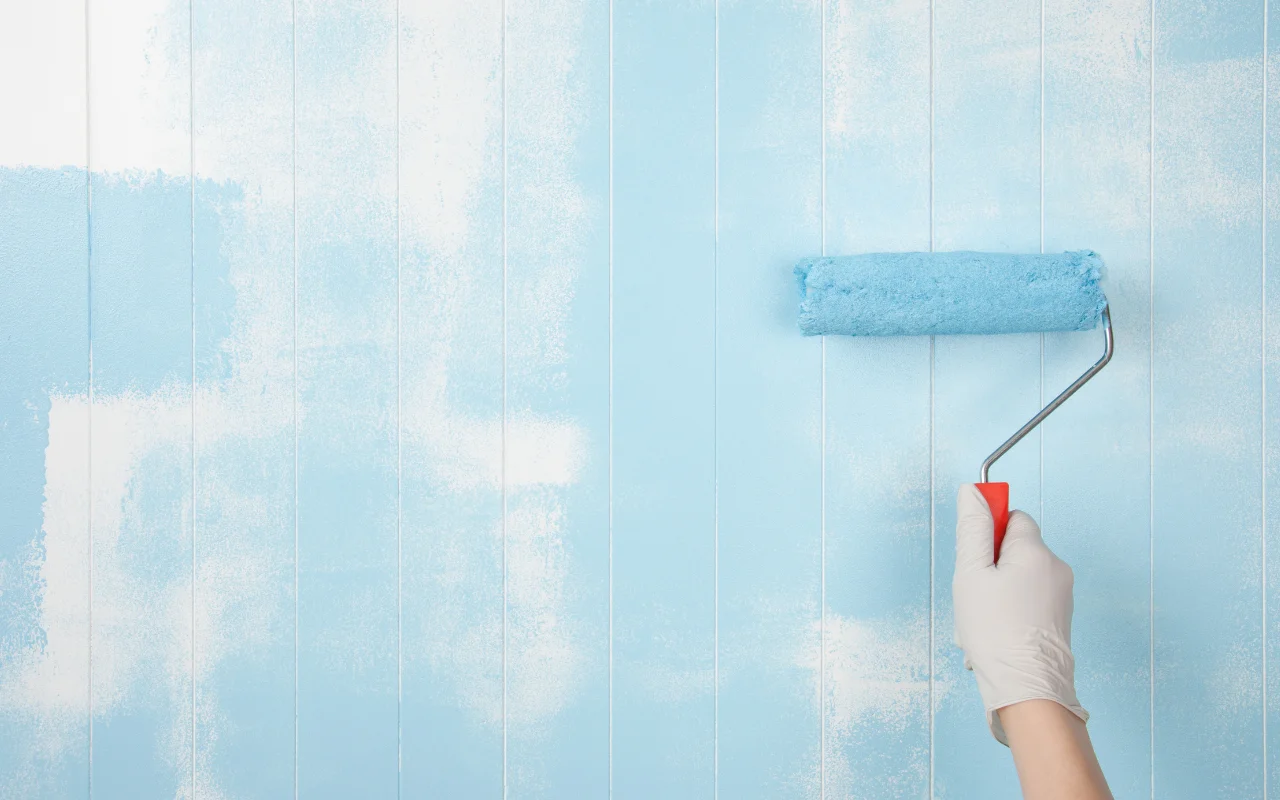 A painter checking the surface of a painted wall to see if it's dry