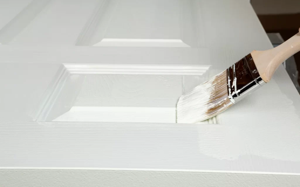 Applying primer to an old painted door using a paintbrush
