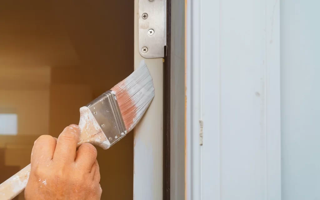 Person sanding a painted door to prepare the surface for a new coat of paint