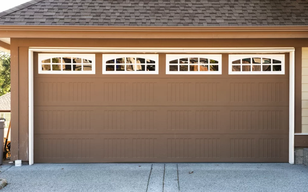 Close-up of a hand applying paint to a metal garage door with a roller